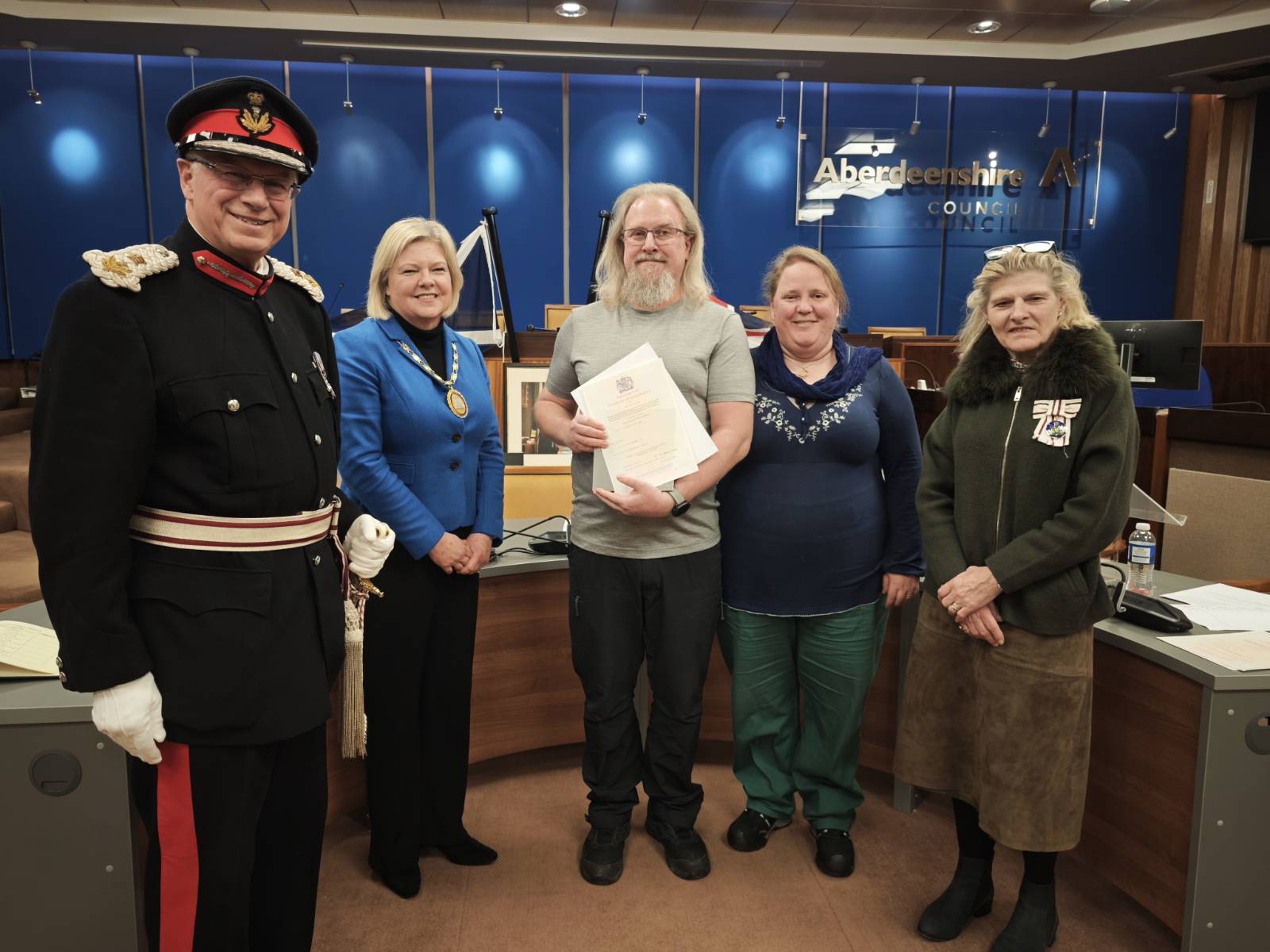 Picture of me holding my citizenship certificate, surrounded by 3 officials and my wife.